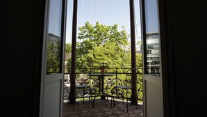 Een balkon met een sierijzeren hekwerk, een tafel en twee stoelen.