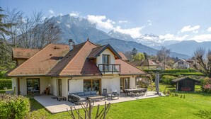 Ein zweistöckiges Haus mit Balkon, einer Terrasse mit Gartenmöbeln und Bergblick.