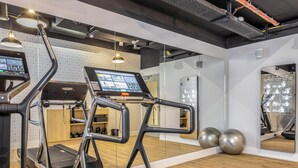 Una palestra moderna con tapis roulant, palle da ginnastica e un monitor digitale che mostra esercizi.