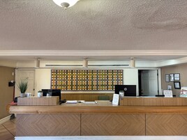 Un mostrador de recepción con detalles de madera, una pared con un diseño llamativo y un techo con textura.