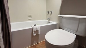 A bathroom with a white bathtub, a toilet, and a shower curtain. - Garden inn and suites san antonio l 35 (San Antonio)