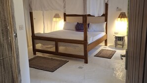 A room with a four-poster bed, two bedside lamps, and a small table with a lamp. - Villa Dolphin (Mtwapa)
