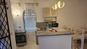 A kitchen with a central island, a stove, a microwave, and a sink. - Villa Dolphin (Mtwapa)