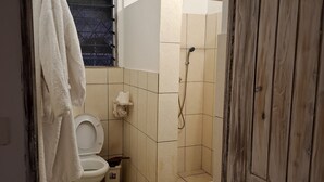 A bathroom with a toilet, a shower, and a towel hanging on the wall. - Villa Dolphin (Mtwapa)