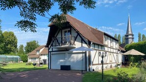 A traditional half-timbered house with a garage, a balcony, and a church steeple in the background. - Chic & Charme Cottage (Suzay)
