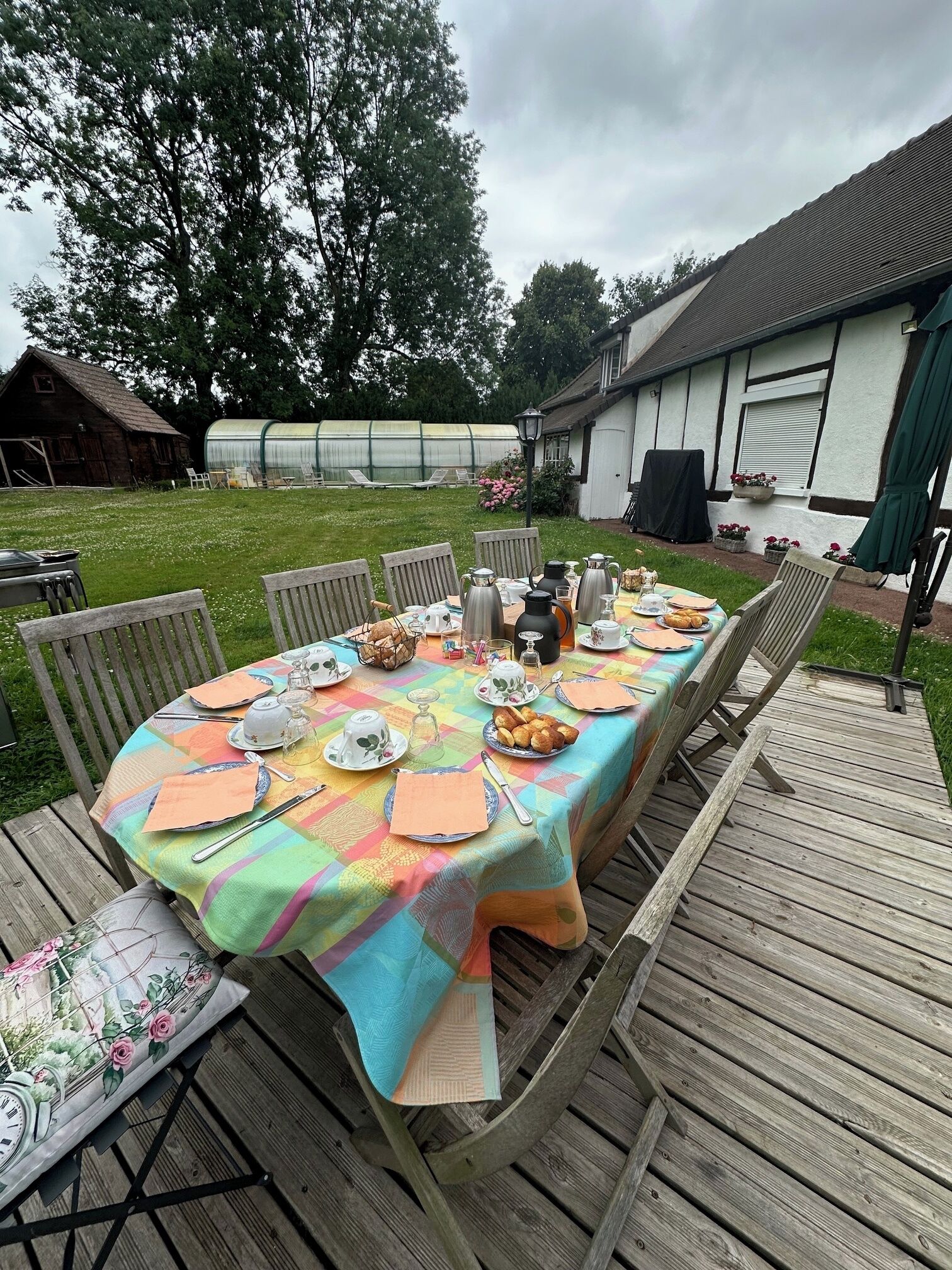 An outdoor dining area with a table set for four, surrounded by wooden chairs.