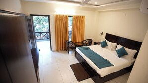 Habitación de hotel con cama, escritorio, silla y balcón con cortinas.