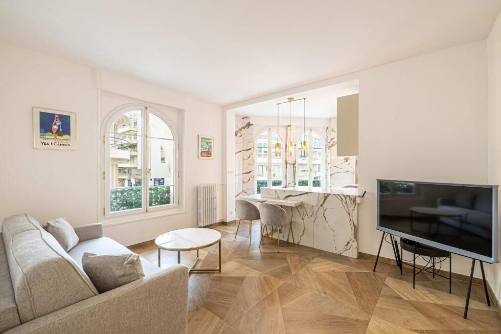 Ein modernes Wohnzimmer mit einer Couch, einem runden Couchtisch, einem Fernseher und einer Kücheninsel aus Marmor.