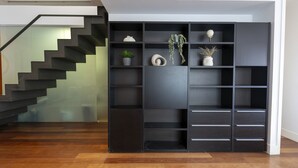 A modern interior with a staircase, a black shelving unit with decorative items, and a wooden floor. - 3 Bedroom Duplex - Spacious, Bright near the Paseo de la Castellana (Madrid)