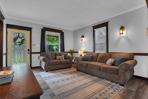 Una sala de estar con un sofá marrón, una mesa de centro de madera y una alfombra estampada.