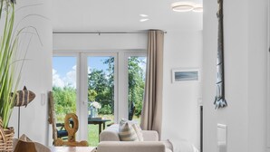 Et moderne interiør med et træskab, en beige sofa og et spiseområde med et bord og stole.