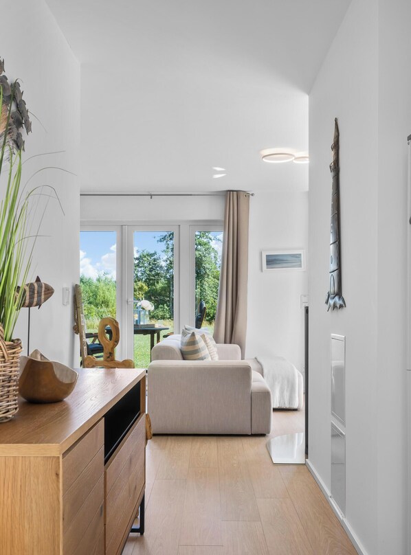 A modern interior with a wooden cabinet, a beige sofa, and a dining area with a table and chairs.