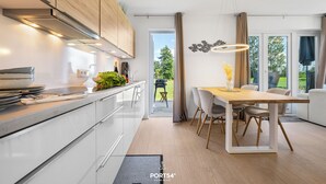 Et moderne køkken med hvide skabe, en træbordplade og en spiseplads med bord og stole.