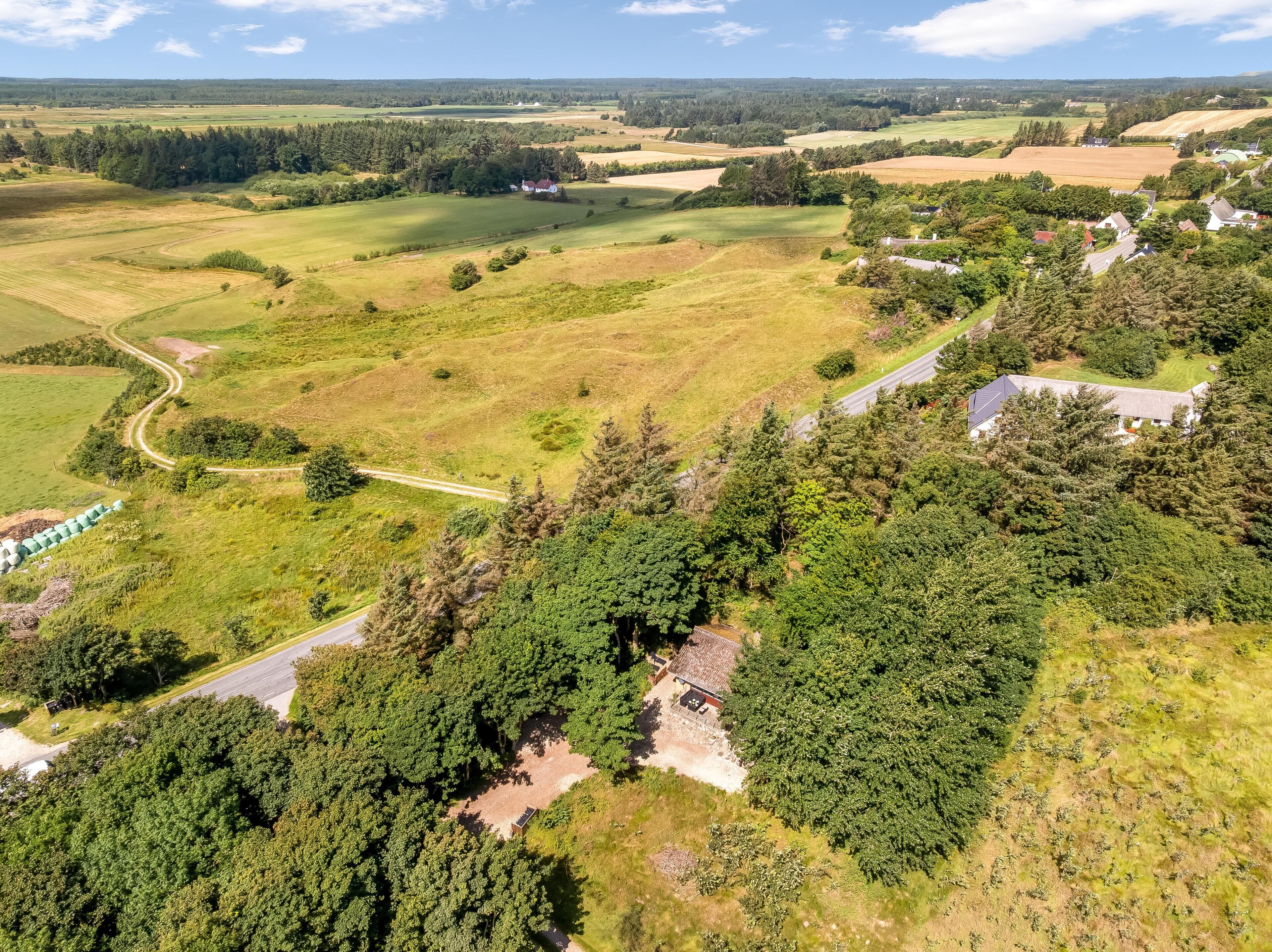 An aerial view of a rural landscape with fields, a winding road, and scattered buildings.