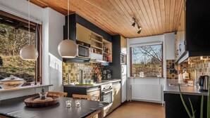 Une cuisine moderne avec des meubles en bois, un plan de travail noir et un coin repas comprenant une table et des chaises.