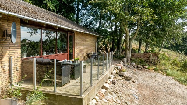Un bâtiment en briques doté d’une structure en verre, d’une terrasse et d’un chemin de gravier.