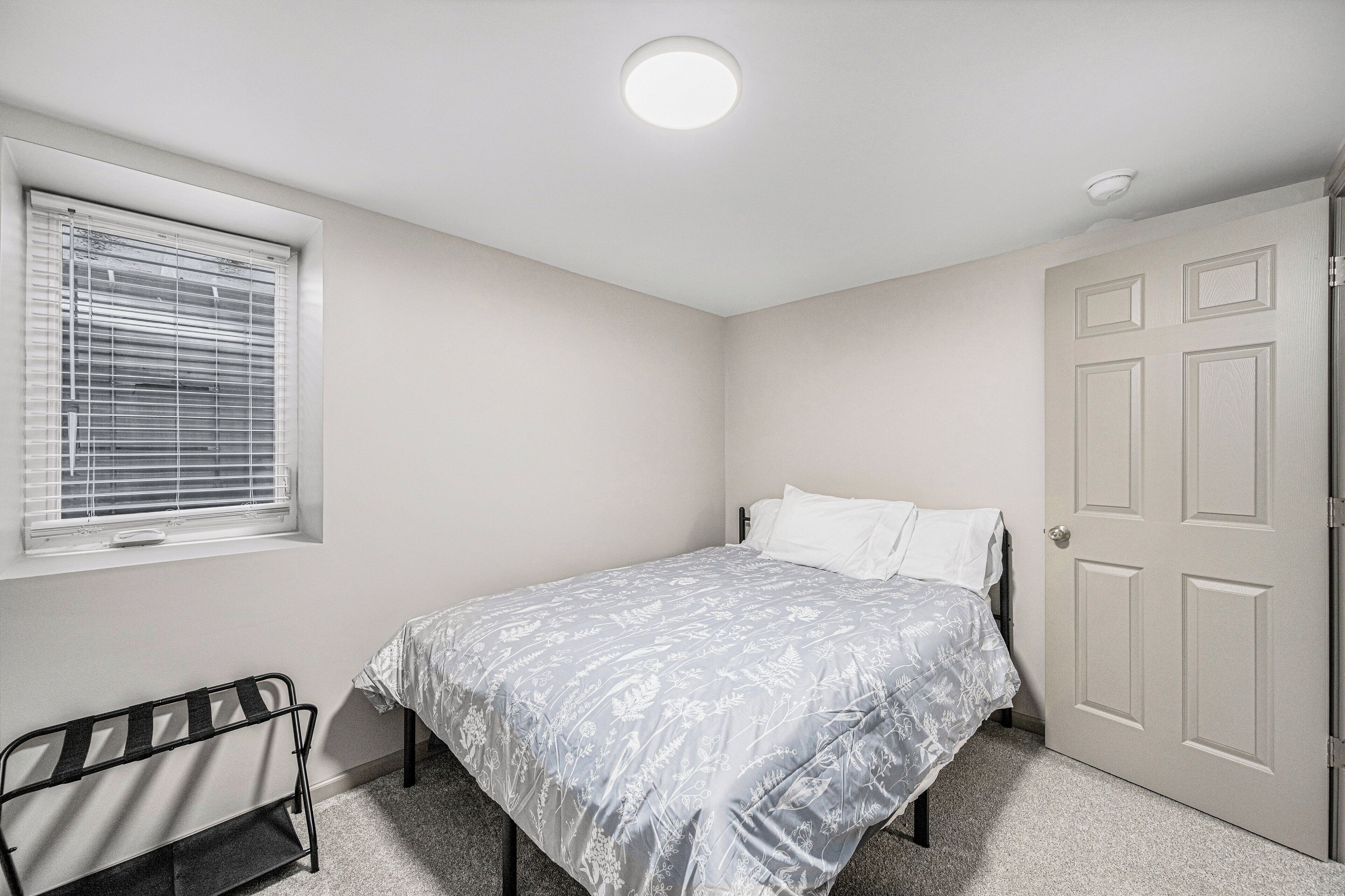 Un dormitorio con una cama individual, una ventana con persianas, una puerta y un radiador.