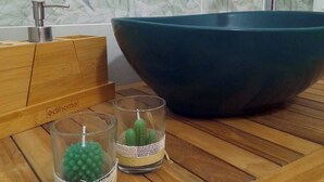 A wooden table with a large blue bowl, two glass candle holders with green beads, and a faucet in the background. - Grandfather's House (Balestrate)