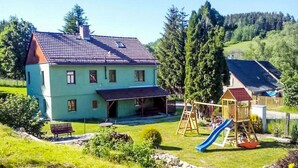 A two-story house with a sloped roof, a patio area, and a playground with a slide. - Wonderful private villa for 11 people with WIFI, terrace and pets allowed (Ceský Krumlov)