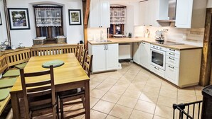 A kitchen with white cabinets, a wooden dining table, and a tiled floor. - Wonderful private villa for 11 people with WIFI, terrace and pets allowed (Ceský Krumlov)