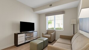 A modern living room with a flat-screen TV, a sofa, a chair, and a small ottoman. - Simplicity At the Rim 1119 I Spacious 1 Bed 1 Bth (San Antonio)