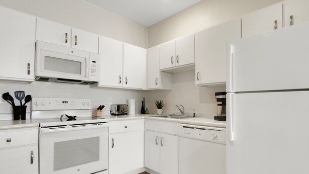 A modern kitchen with white cabinetry, a microwave, stove, and refrigerator. - Simplicity At the Rim 1119 I Spacious 1 Bed 1 Bth (San Antonio)