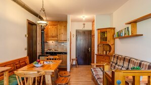 A cozy kitchen with wooden cabinets, a dining table with chairs, and a sofa.
