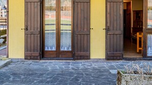 A building with a yellow exterior, wooden doors with glass panels, and a stone-paved entrance.