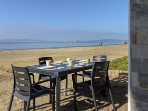 A table set for two with chairs, overlooking a beach with a calm sea and distant mountains. - Wonderful private villa for 6 guests with A/C, WIFI, balcony and pets allowed (Follonica)