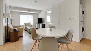 Un salon moderne avec une table à manger ronde, deux canapés, un téléviseur et un lave-linge.