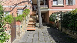 Ein schmaler Steinweg führt zu einem roten Backsteinhaus mit einer Holztreppe.