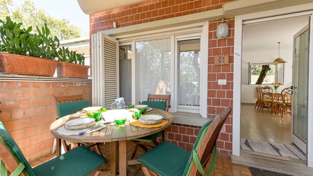 Eine Terrasse mit einem runden Esstisch, umgeben von grünen Sitzgelegenheiten.