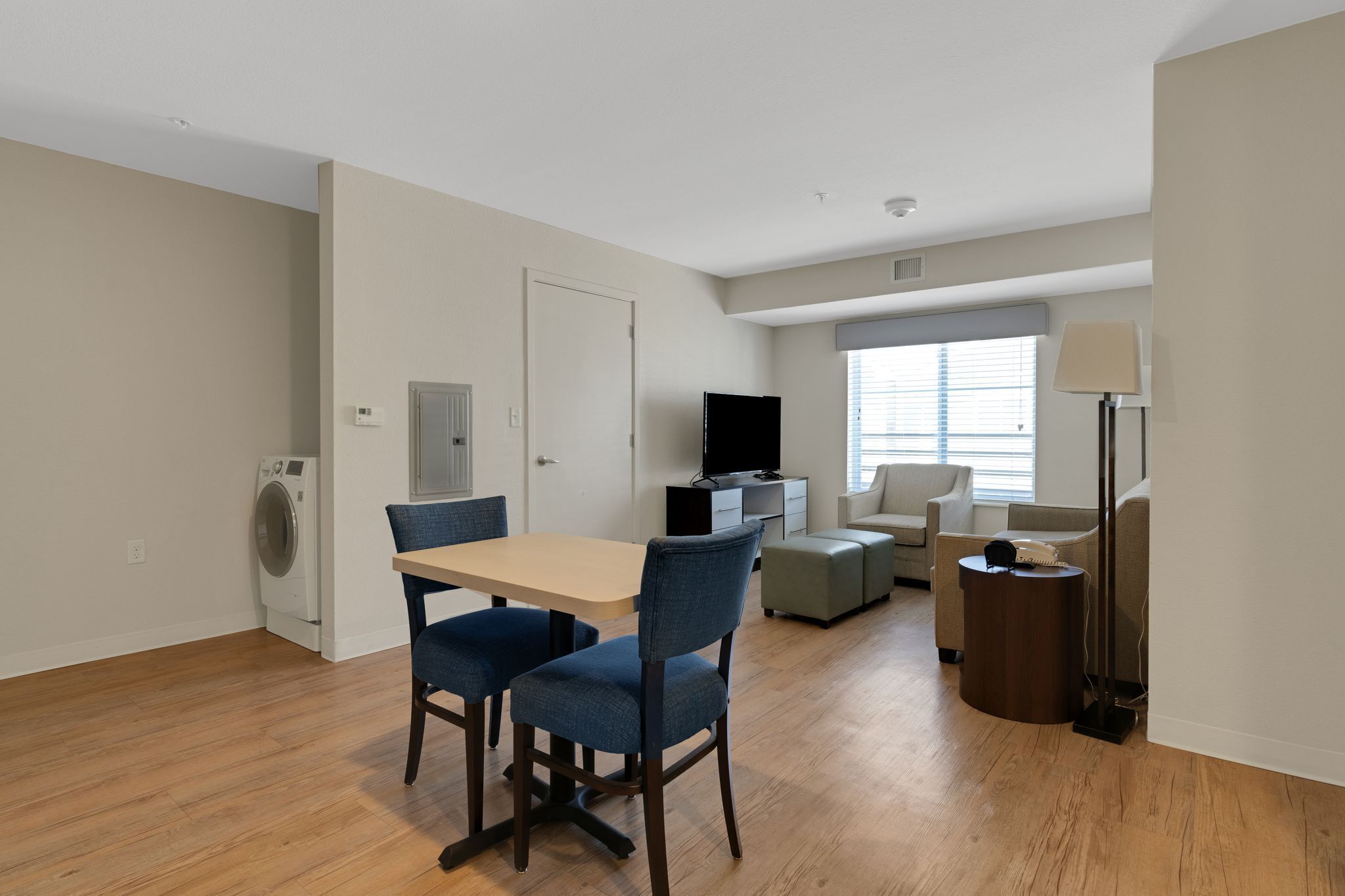 A modern living room with a dining area, a flat-screen TV, a sofa, and a lamp.