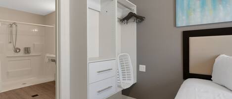 Une chambre à coucher avec un lit, un dressing, une douche et un tableau au mur.