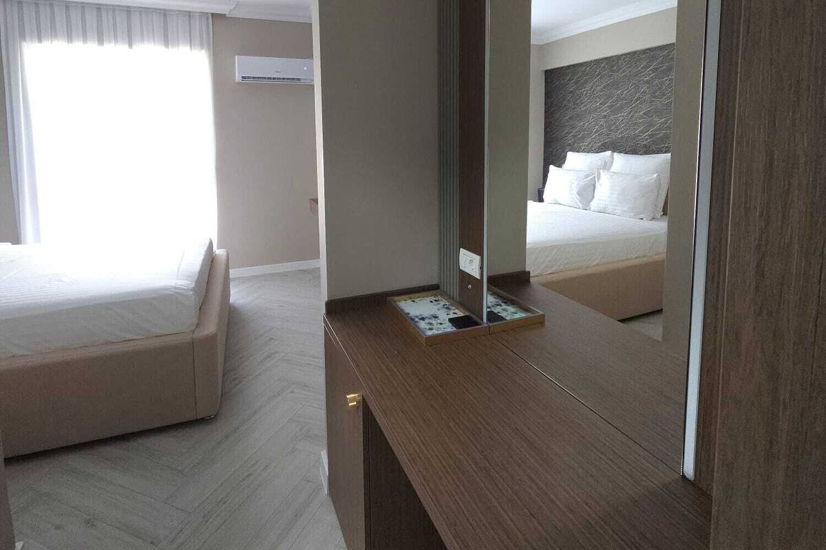 A hotel room with a large bed, a wooden desk, and a mirror.