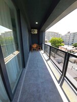 A balcony with a table and chairs, a ceiling fan, and a view of buildings and trees.