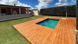 A backyard with a wooden deck, a swimming pool, and a hedge. - Villa Amos Marzamemi San Lorenzo (San Lorenzo)