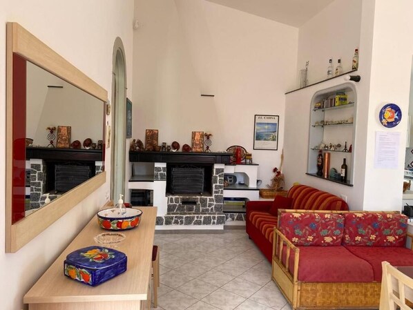 Una sala de estar con chimenea, un sofá, una mesa de comedor y un espejo.