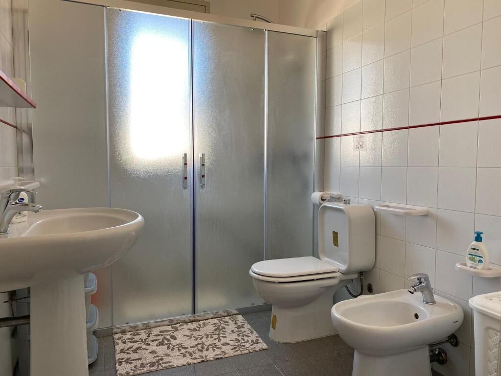 A bathroom with a toilet, bidet, and two sinks.
