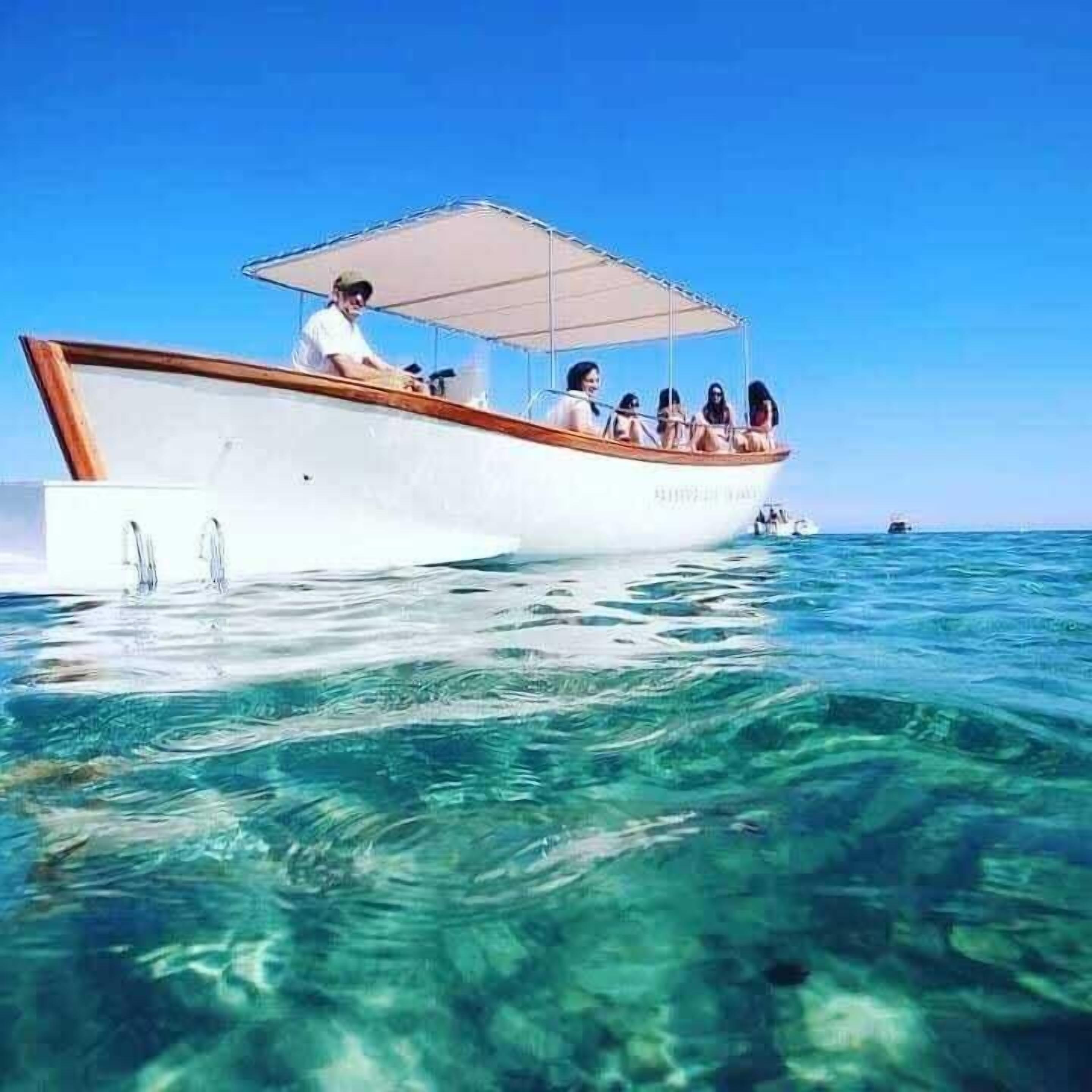 Un bote con pasajeros, agua cristalina y otro bote a lo lejos.