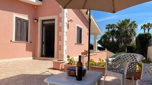 An outdoor patio with a table, chairs, and potted plants. - Villa Amos Marzamemi San Lorenzo (San Lorenzo)