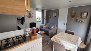 A compact living space with a kitchenette, a dining area, and a sofa. - Comfortable mobile home near the Atlantic (Talmont-Saint-Hilaire)