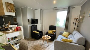 A compact living space with a kitchenette, a sofa, a chair, and a television. - Comfortable mobile home near the Atlantic (Talmont-Saint-Hilaire)