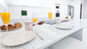A modern kitchen with white countertops, a glass of orange juice, a floral mug, and a plate of pastries. - Contemporary house with private pool on Costa Brava (Roses)