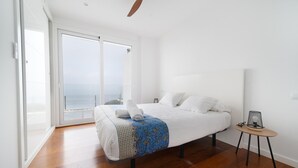 A bedroom with a bed, a small table, a ceiling fan, and a view of the sea through a sliding door. - Contemporary house with private pool on Costa Brava (Roses)