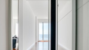 A hallway with a view of the sea through large windows, leading to a room with a bed and a chair. - Contemporary house with private pool on Costa Brava (Roses)