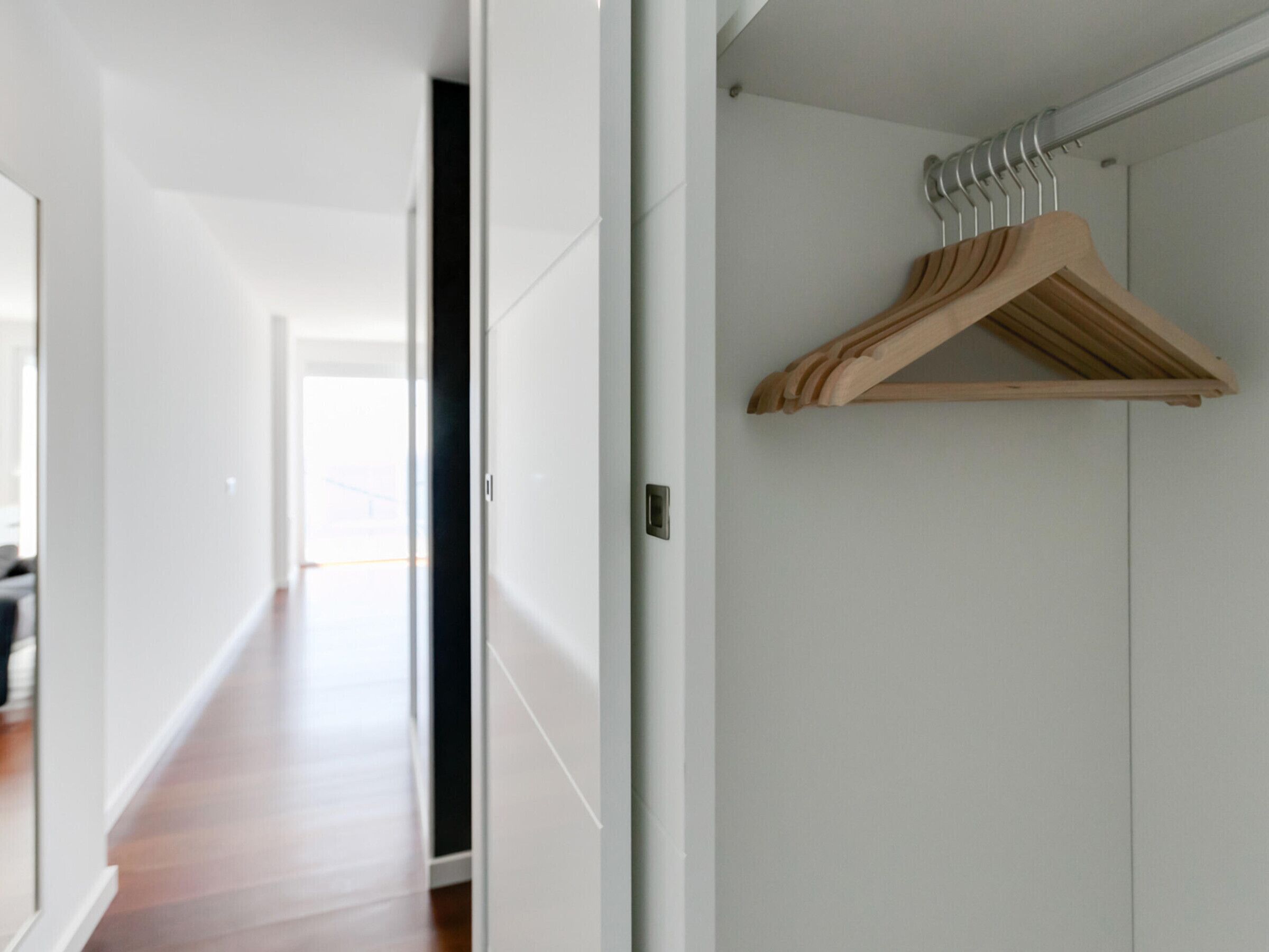 Un pasillo con un perchero de madera en la pared, que conduce a una habitación con una puerta.