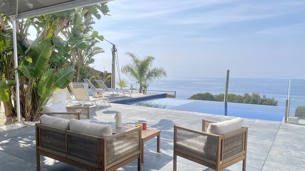 A terrace with a pool, lounge chairs, and a view of the sea. - Contemporary house with private pool on Costa Brava (Roses)