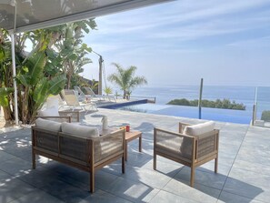A terrace with a pool, lounge chairs, and a view of the sea. - Contemporary house with private pool on Costa Brava (Roses)