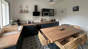 Een moderne keuken met een houten eettafel, rieten stoelen en een ingebouwde oven.